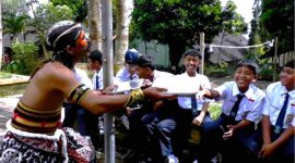 Petugas Satuan Pelayanan Pemenuhan Gizi (SPPG) Danupayan mengantarkan Makan Bergizi Gratis (MBG) dengan mengenakan kostum kesenian Warok